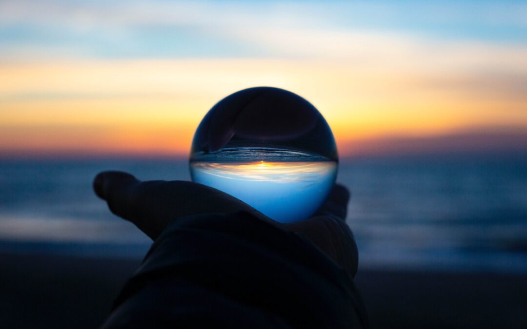 Crystal ball held up in front of sunset, inverting the scene